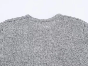 Close-up of a grey knit sweater showing reinforced crew neck collar and fine texture