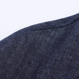 Gros plan sur la texture du denim bleu foncé et les coutures précises de la robe