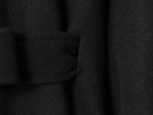 Detailed macro view of heavy black wool fabric texture and clean belt loop stitching