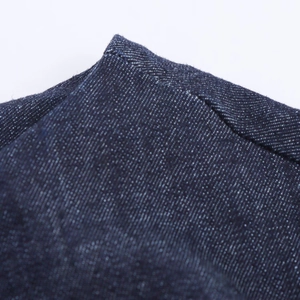 Macro du denim bleu foncé montrant la texture sergé et les surpiqûres de la robe