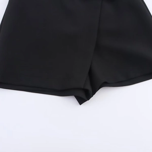 Detail of black asymmetric skirt shorts with smooth fabric and overlapping panel design