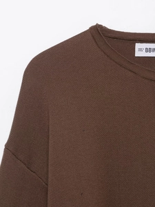 Close-up of a brown knit sweater featuring a ribbed crew neck and high-quality fabric texture