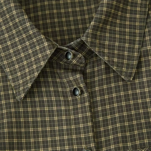 Close-up of padded shoulder plaid shirt jacket with black metallic buttons and sharp collar