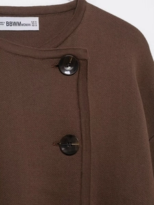 Detail of dark brown knit cardigan showing tortoiseshell buttons and textured weave