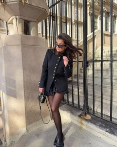 Close-up of a black standing collar blazer with stylish metallic buttons on street