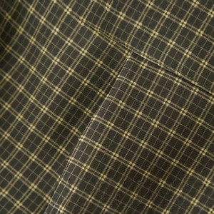 Detailed view of checkered plaid shirt fabric in olive green with precise stitching
