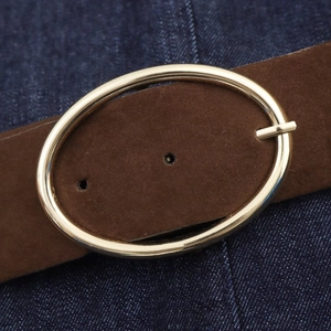 Détail de la ceinture en daim marron foncé avec boucle ovale dorée sur denim
