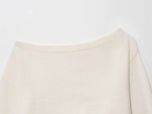 Détail d'un pull en maille blanc cassé montrant la texture côtelée du col Bardot