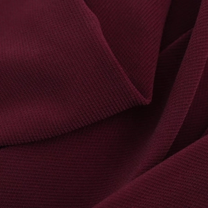 Detail shot showing the fine texture and elegant pleated draping of dark red fabric