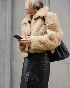 Detail of short camel faux fur jacket with large collar and black buttons on street model