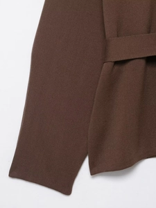 Detail of dark brown knit coat featuring fine stitch texture and matching waist belt