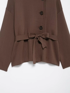 Detail view of brown knit cardigan with a large side button and matching waist tie belt