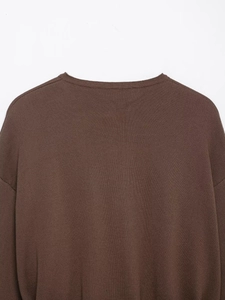 Close-up of ribbed crewneck and textured knit on a dark brown sweater for women