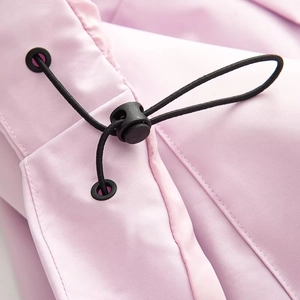Close-up of pink outdoor jacket fabric showing black drawstring toggles and fine texture