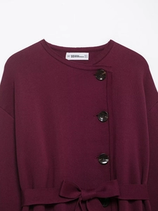 Close-up of burgundy knit cardigan with marble buttons and elegant waist belt detail