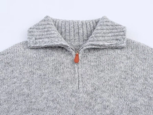 Detail of grey half-zip knit sweater showing silver zipper and brown leather pull tab