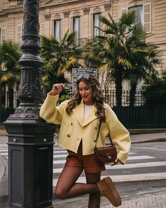 Scatto street style di una donna con un cappotto corto a doppiopetto in lana giallo