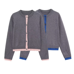 Detail of grey knitted cardigan showing pink and blue contrast trim and button closure