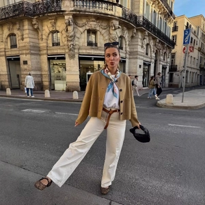 Chic women's brown suede aviator jacket with white trousers and leopard flats in street style