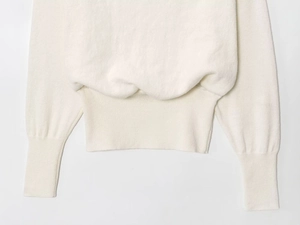Vue détaillée des poignets et de l'ourlet côtelés d'un pull en maille blanc ajusté