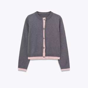 Detail of knit cardigan showing charcoal grey fabric with pink trim and buttons