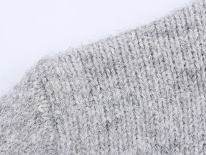 Macro shot of light gray chunky knit sweater fabric with soft wool texture and fine fibers