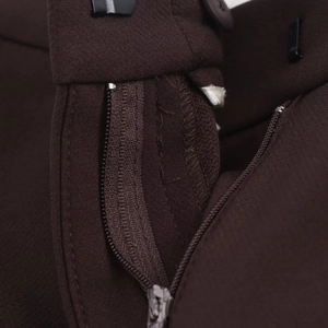 Detailed macro view of the zipper fly and reinforced stitching on high-waist brown trousers