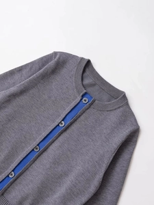 Close-up of grey knit cardigan showing contrast blue inner placket and sewing details