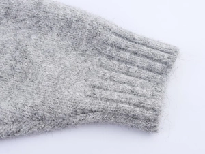 Close-up detail of grey chunky knit sweater showing rib-knit cuffs and fuzzy wool texture