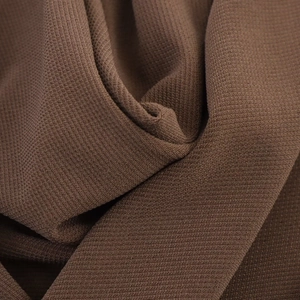 Close-up of brown dress fabric showing dense vertical textures and waffle-like knit structure