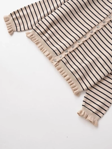 Détail d'un cardigan en maille rayée avec poignets à volants étagés et fermeture boutonnée