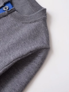 Detailed close-up of grey knit cardigan neckline with blue trim and round collar