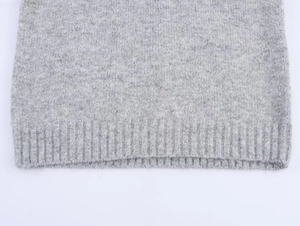 Macro shot of light gray sweater featuring soft knit texture and ribbed hem detail