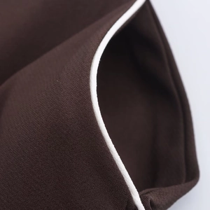 Macro shot of dark brown woven fabric showing fine white piping detail and textile texture