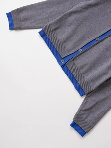 Detail of grey knitted cardigan showing blue ribbed cuffs and round buttons closeup