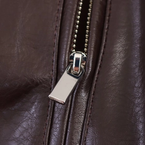 Macro shot of silver metal zipper on dark brown faux leather pilot jacket texture