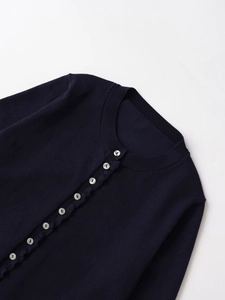 Détails d'un cardigan en tricot bleu marine avec boutons nacrés et encolure ronde