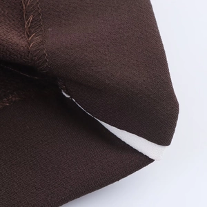 Close-up of brown knit fabric showing precision edge stitching and white elastic band detail