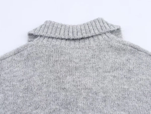 Close-up of marl grey knit sweater featuring a ribbed high collar and wool blend texture