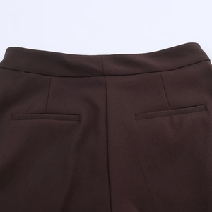 Detail of welt pockets and clean stitching on deep brown high-waisted tailored trousers