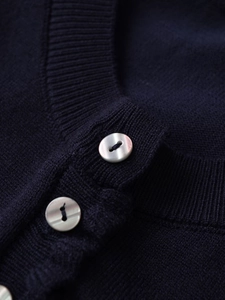 Gros plan détaillé d'un cardigan en maille bleu marine avec boutons perlés et col côtelé
