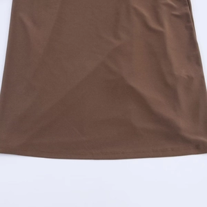 Detail of a brown pleated dress hem featuring double-needle stitching on high-quality fabric