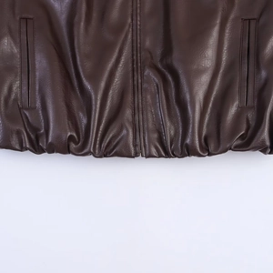 Detail of dark brown faux leather bomber jacket showing elastic hem and zipper closure