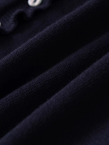 Détail du tissu en maille bleu marine avec des boutons perlés sur un cardigan