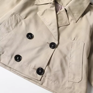 Detail of short khaki trench coat with double-breasted buttons and wide lapels