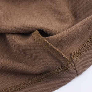 Macro shot of dark brown ribbed knit fabric showing detailed flatlock stitching and hem