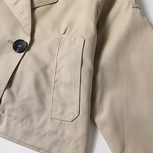 Detail view of khaki short trench coat featuring notched lapels and round black buttons