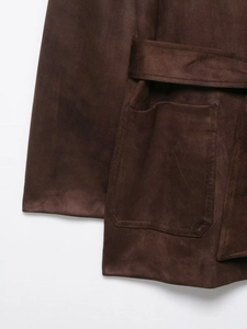 Detail of dark brown faux suede jacket featuring a square patch pocket and fine stitching