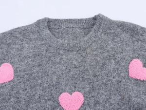 Dettaglio maglione grigio in maglia con motivo a cuore rosa testurizzato e scollo rotondo