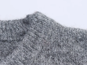 Dettaglio ravvicinato del maglione in maglia grigia con morbida trama in mohair